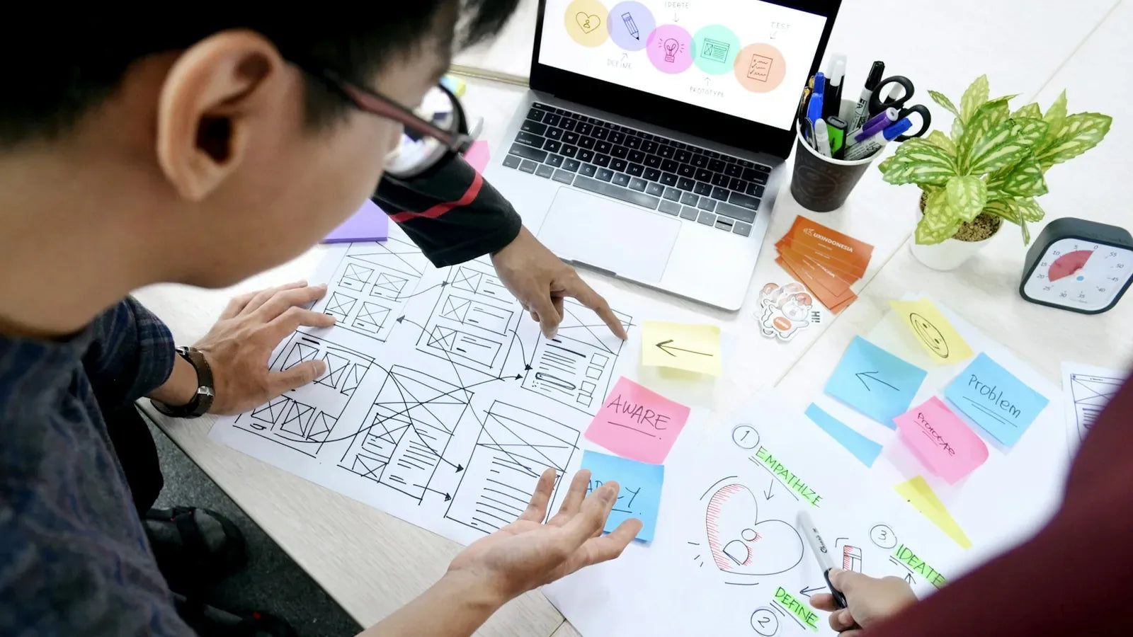 Man designing wireframes at desk with laptop.