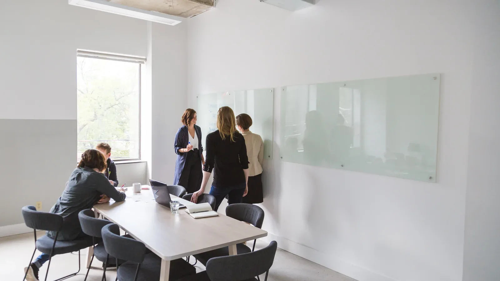 Team discussing a project around a table and whiteboard in an office.