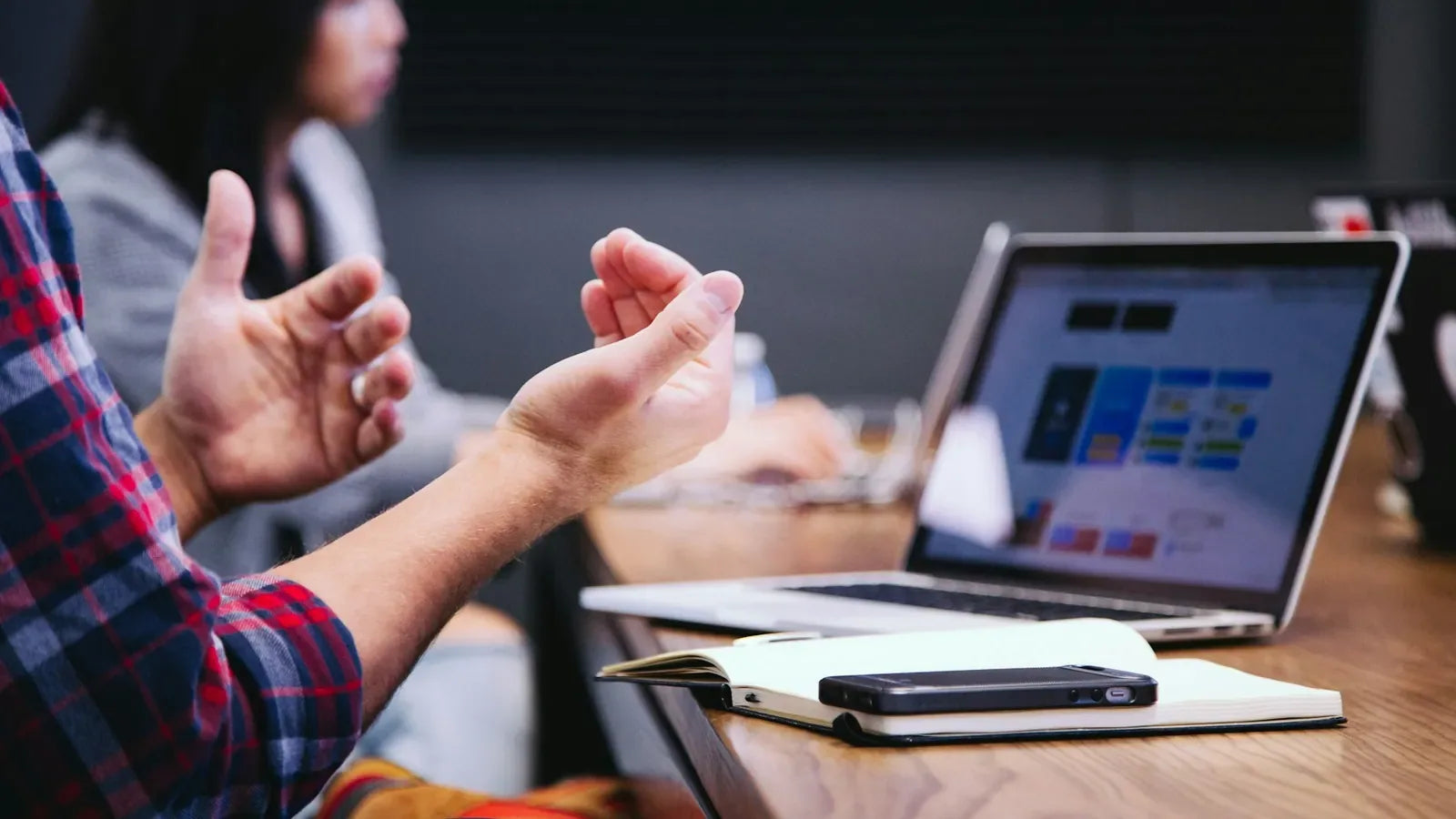 Person gesturing during meeting with laptop.
