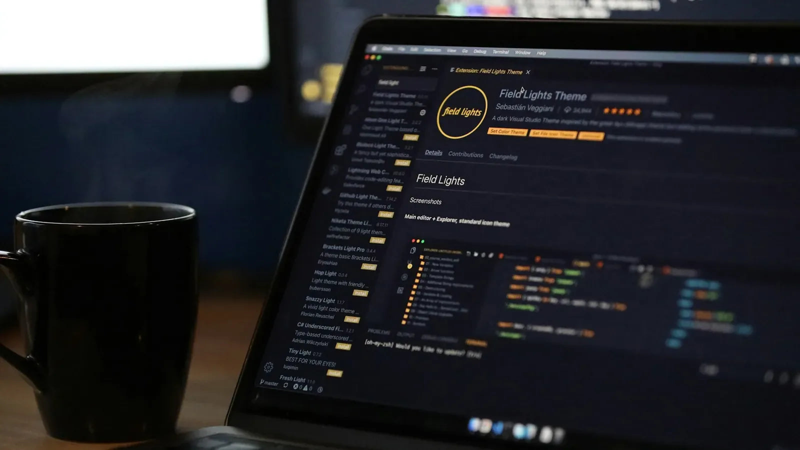 A laptop screen displaying code and a steaming mug on a desk.
