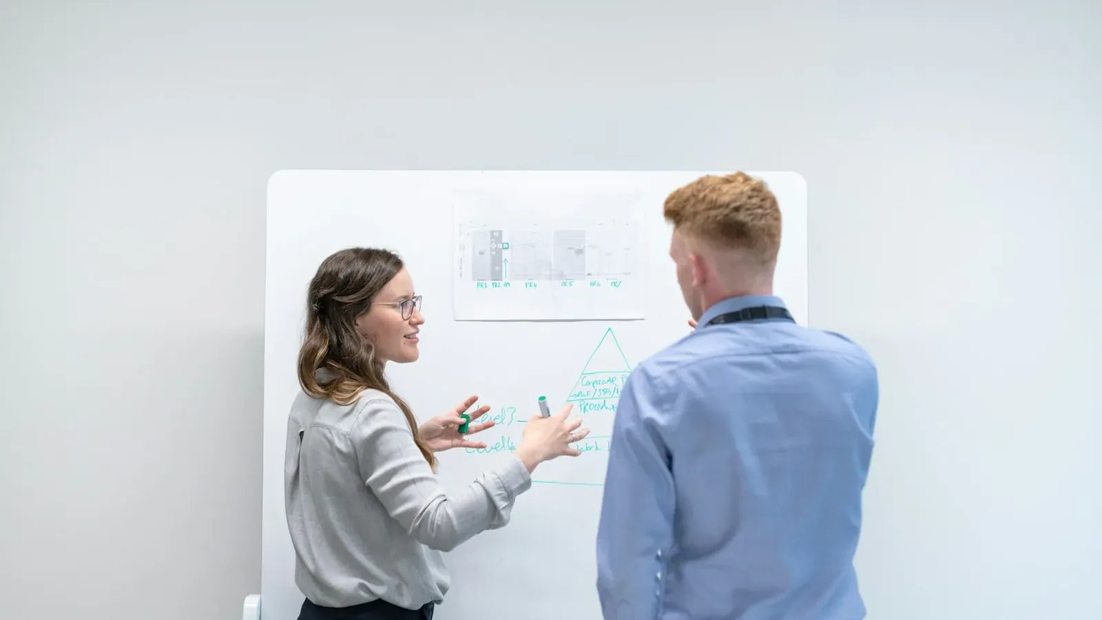 Two colleagues discussing ideas at whiteboard.