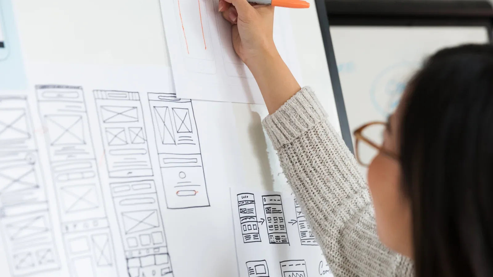 Designer revising mobile interface wireframes on a whiteboard.