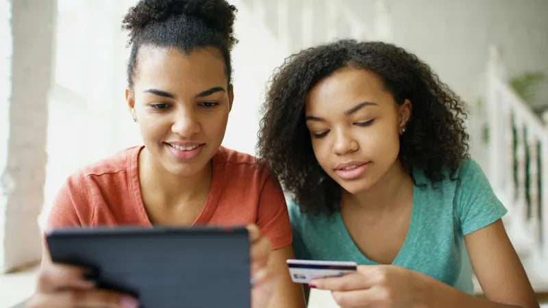 Two shoppers reviewing a purchase on a tablet with a payment card