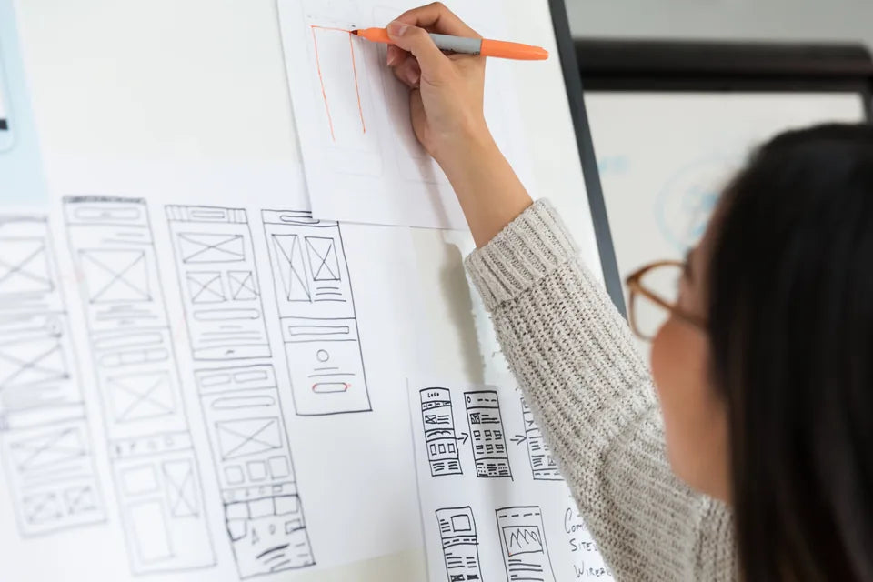 Designer refining mobile wireframes on a wall